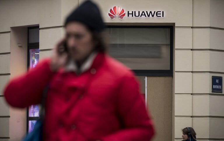 People pass by a Huawei logo above the entrance of a Huawei store in Paris