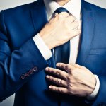 Businessman in blue suit tying the necktie