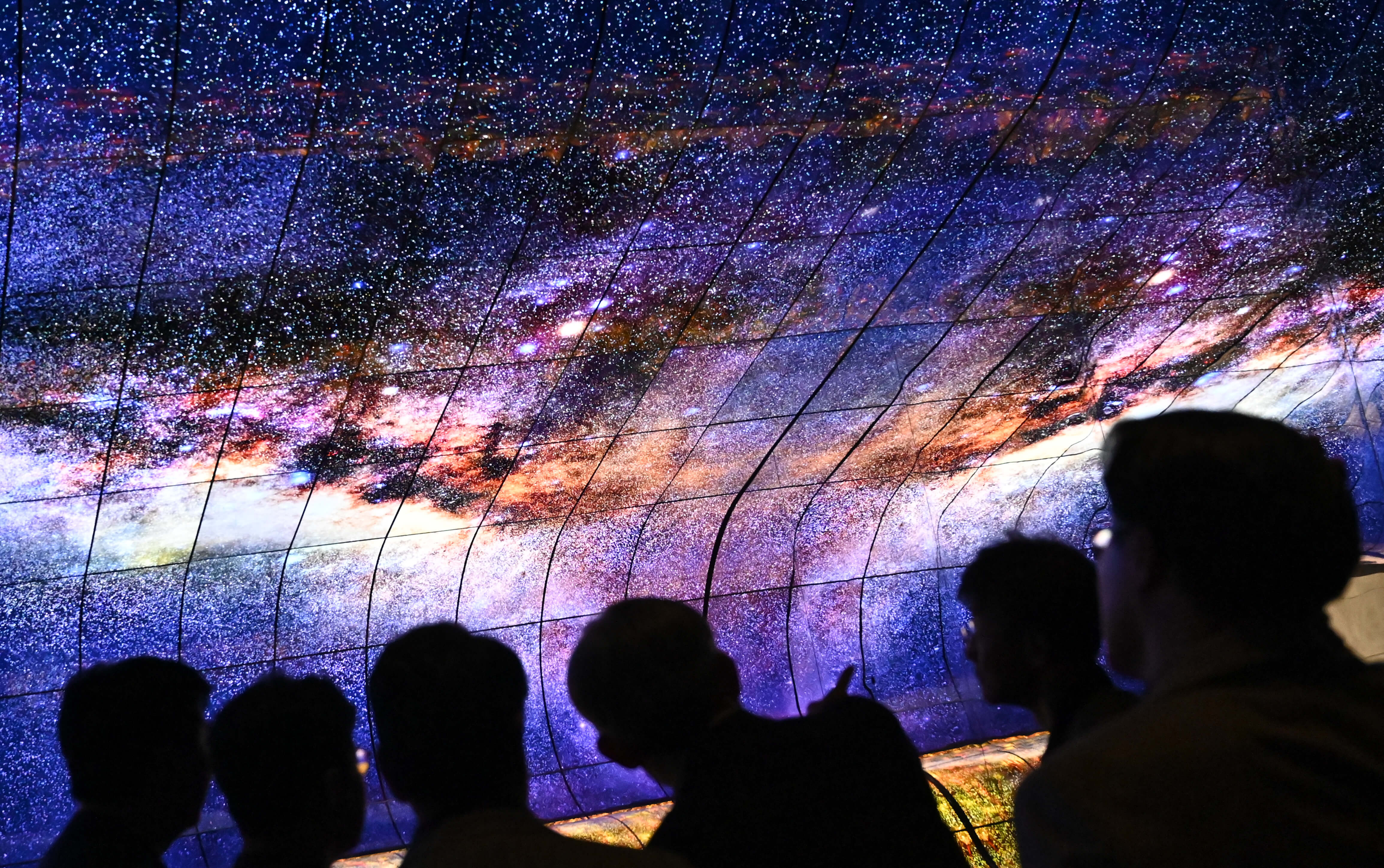 People watch a television installation at the booth of LG during a press preview at the IFA in Berlin