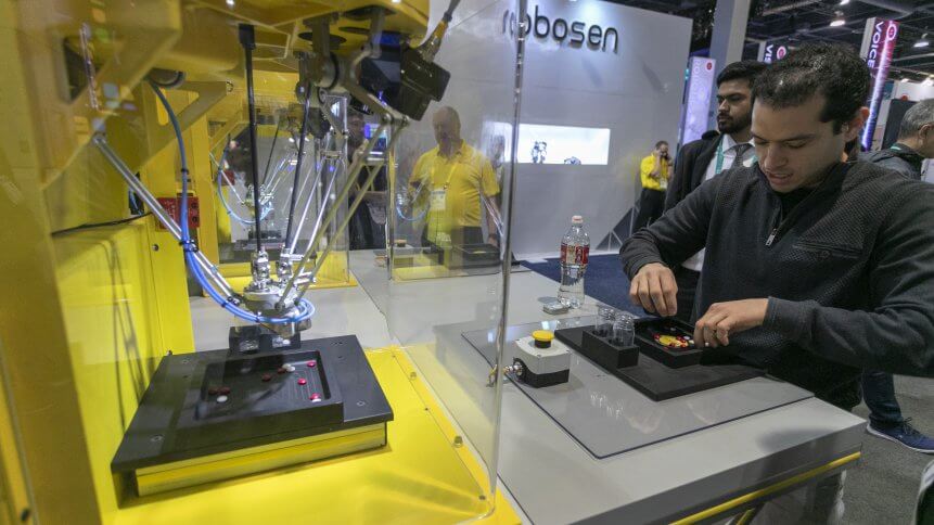 A man races against the speed of a FANUC robot sorting colored objects at the 2020 Consumer Electronics Show
