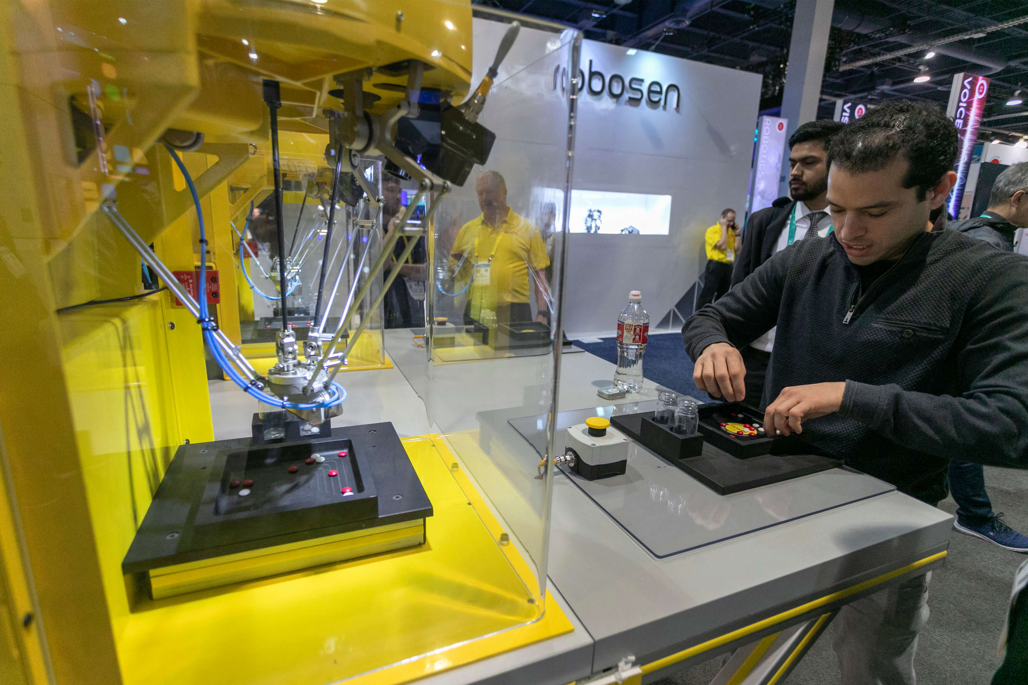A man races against the speed of a FANUC robot sorting colored objects at the 2020 Consumer Electronics Show