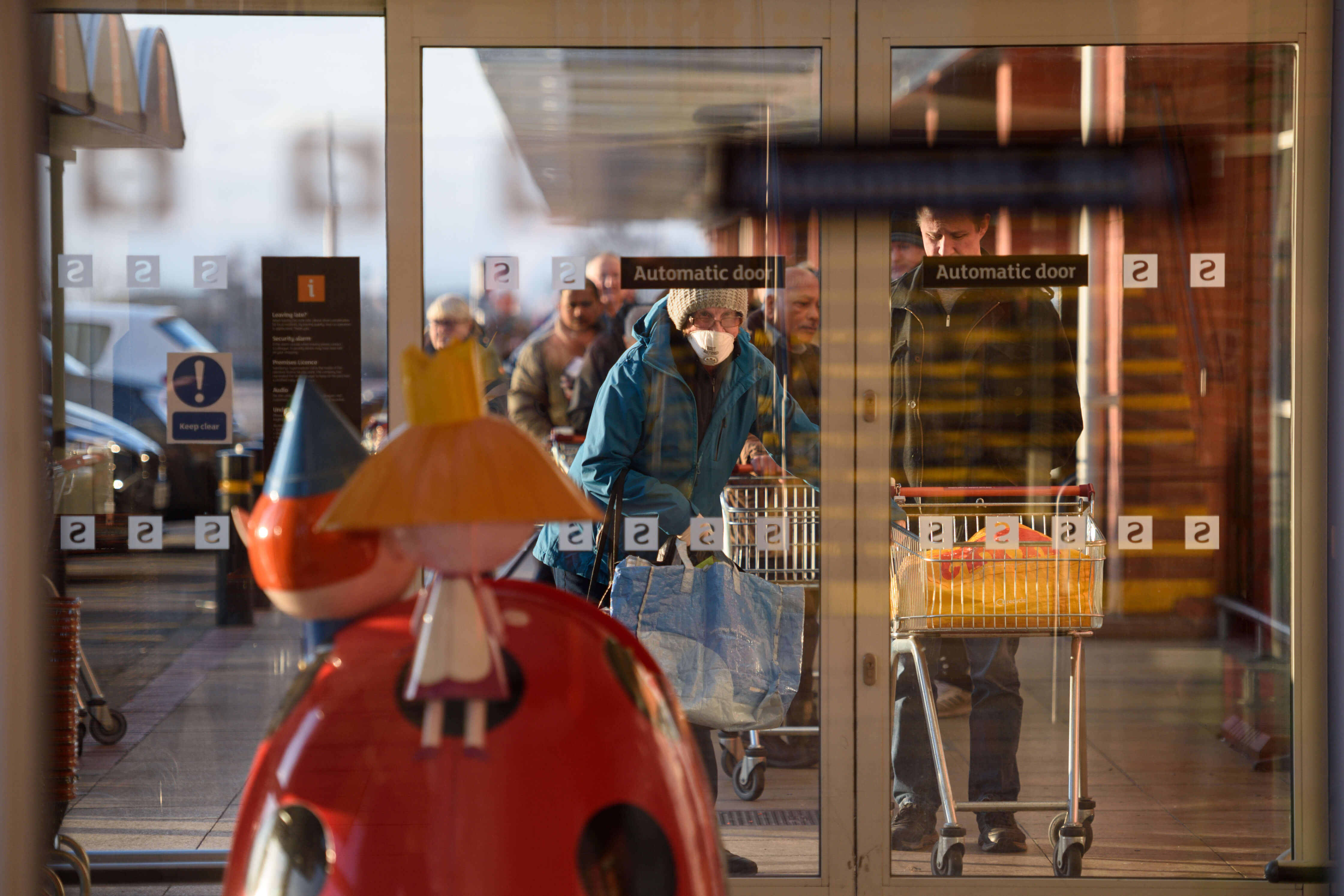 Shoppers queue before the 7am opening time to enter a Sainsbury's supermarket in Oldham, northern England, on March 20, 2020.