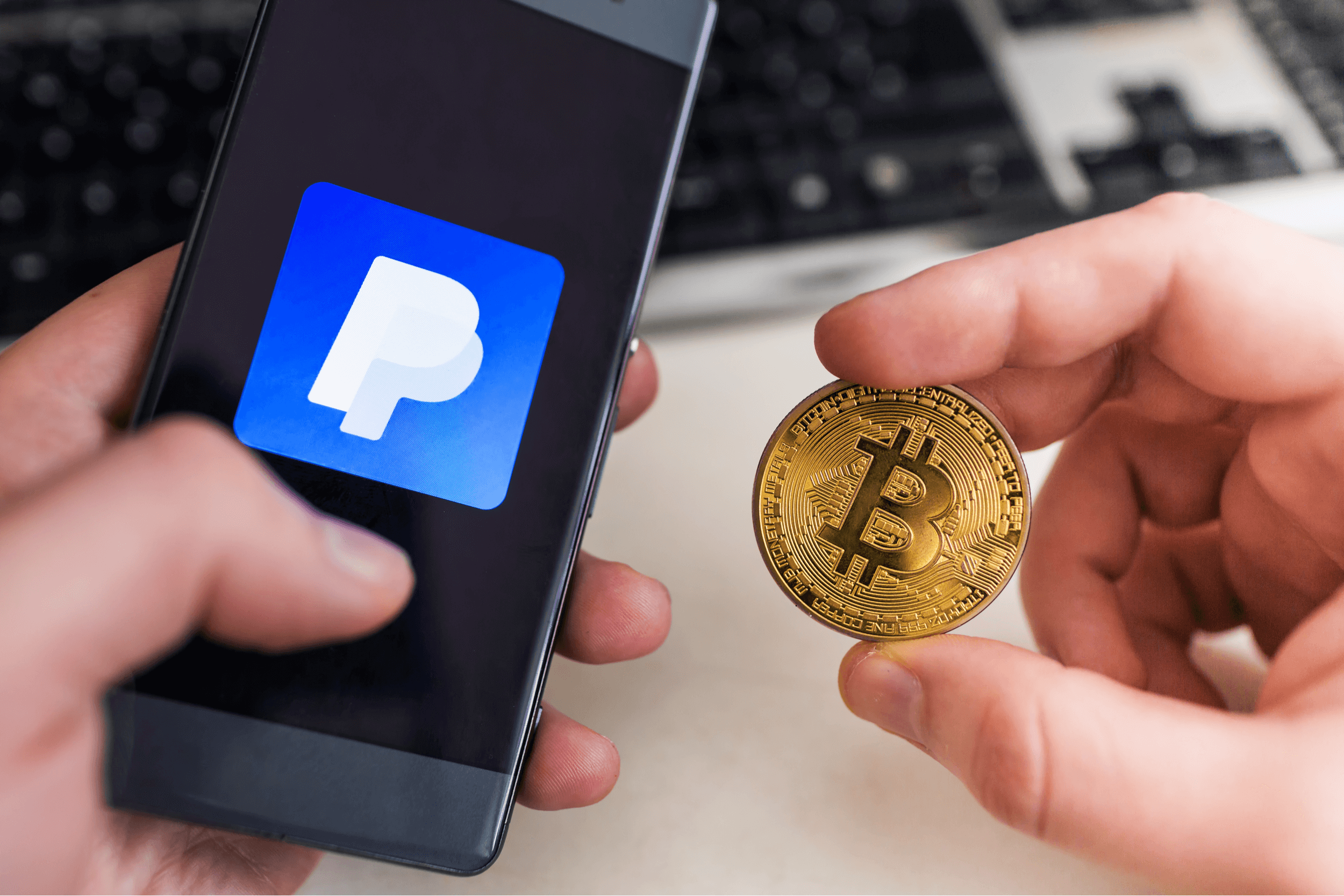 Man holding Bitcoin coin and in other hand smartphone with Paypal application.