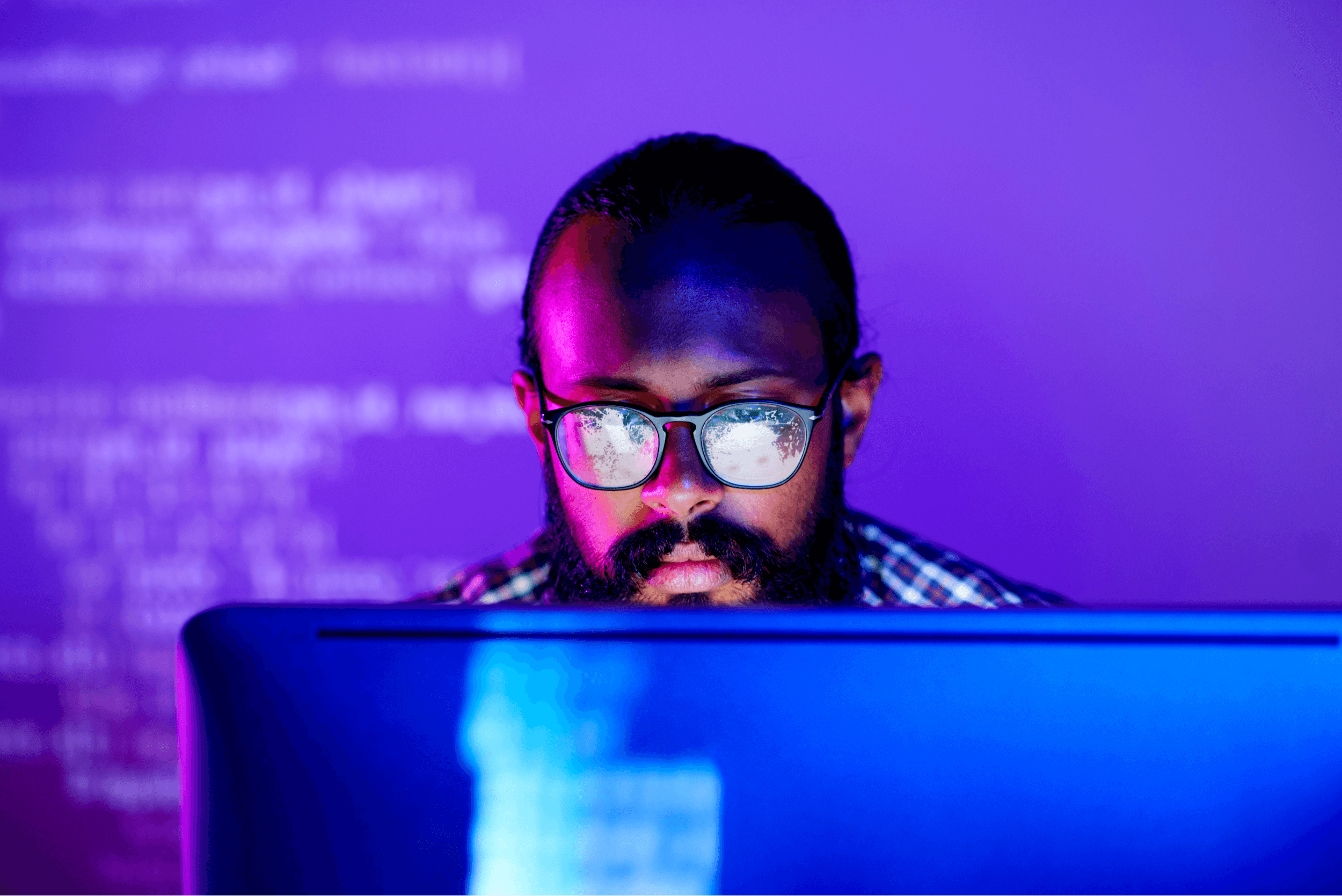 Young serious programmer in eyeglasses concentrating on working with coded data on computer screen