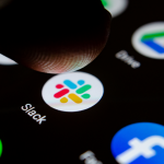 Close up photo Slack app on the smartphone screen and a finger launching it. The top app for communication and collaboration.