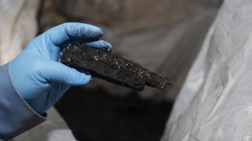 A worker holds a piece of black mass — a mix of lithium, nickel, cobalt, and graphite — at the Li-Cycle lithium-ion battery recycling facility in Ontario in 2021.