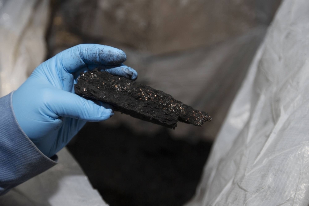 A worker holds a piece of black mass — a mix of lithium, nickel, cobalt, and graphite — at the Li-Cycle lithium-ion battery recycling facility in Ontario in 2021.