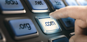 Finger pushing '.com' button to choose top-level domain. Source Shutterstock