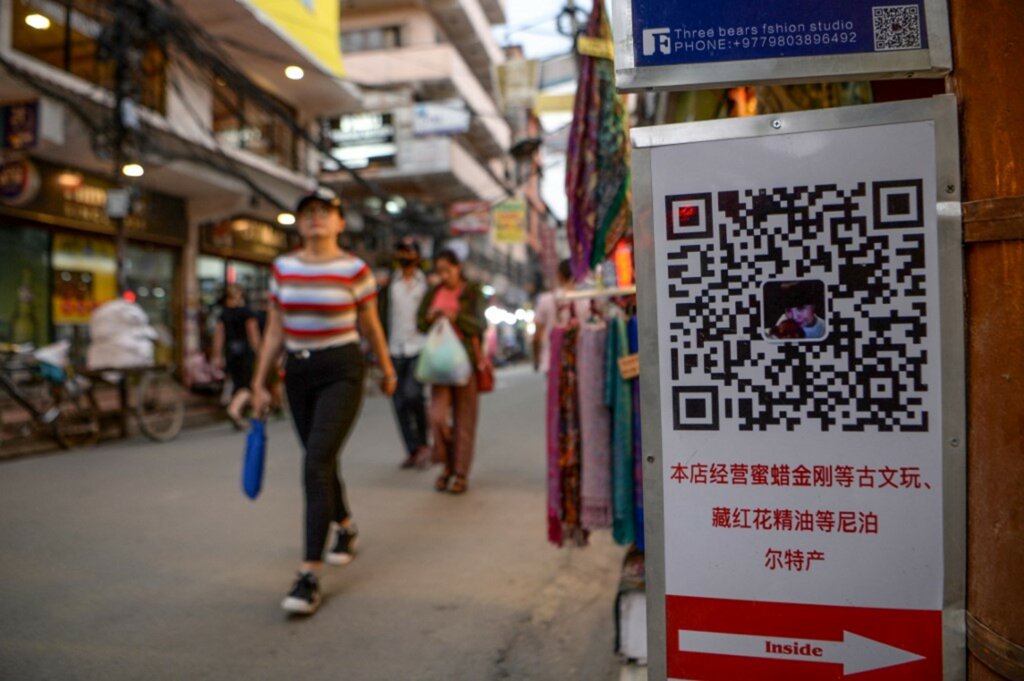 Chinese tourists walk past a QR code.