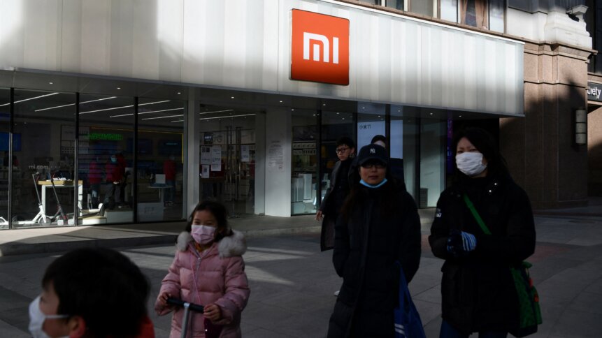 People walk past a Xiaomi store in Beijing, China on January 15, 2021, as shares in the company collapsed on January 15 after the United States blacklisted the smartphone giant and a host of other Chinese firms. (Photo by GREG BAKER / AFP)