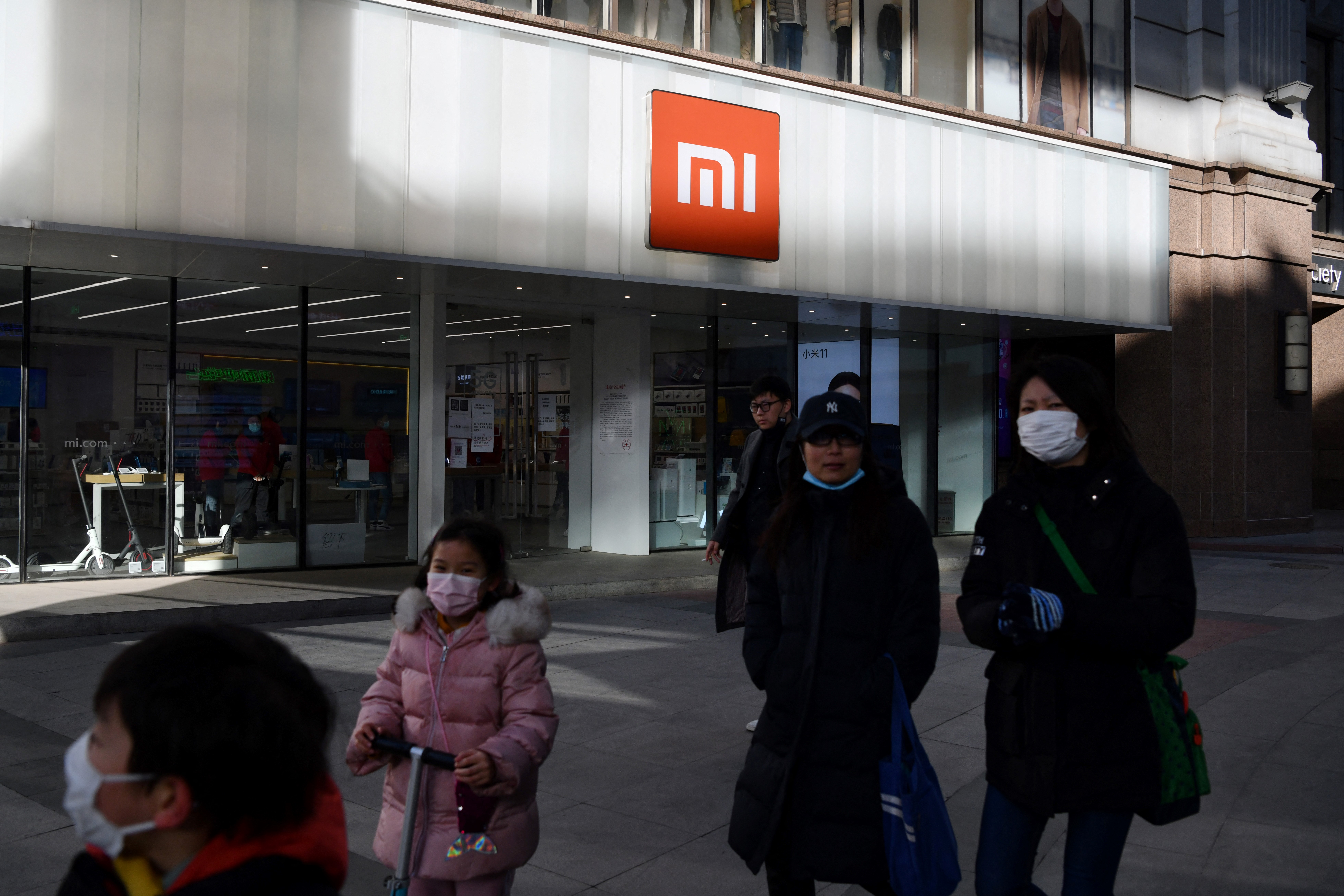 People walk past a Xiaomi store in Beijing, China on January 15, 2021, as shares in the company collapsed on January 15 after the United States blacklisted the smartphone giant and a host of other Chinese firms. (Photo by GREG BAKER / AFP)