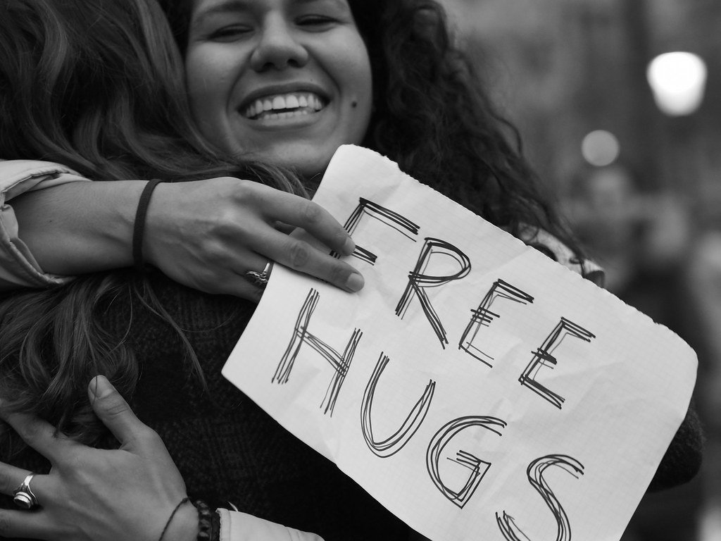 Illustrative image for article on DeepSeek, comprising a woman holding a sign that reads 'free hugs'.
